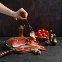 Italian dry-cured ham prosciutto on wooden cutting board